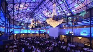 Blue-Lit Conference Hall With Grand Chandelier And Seating Arrangement For Oipeec Book Store Event.